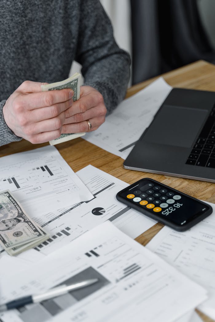 Mastering the First Impression: Your intriguing post title goes here Hands counting money at a workspace with a laptop, calculator, and financial documents.