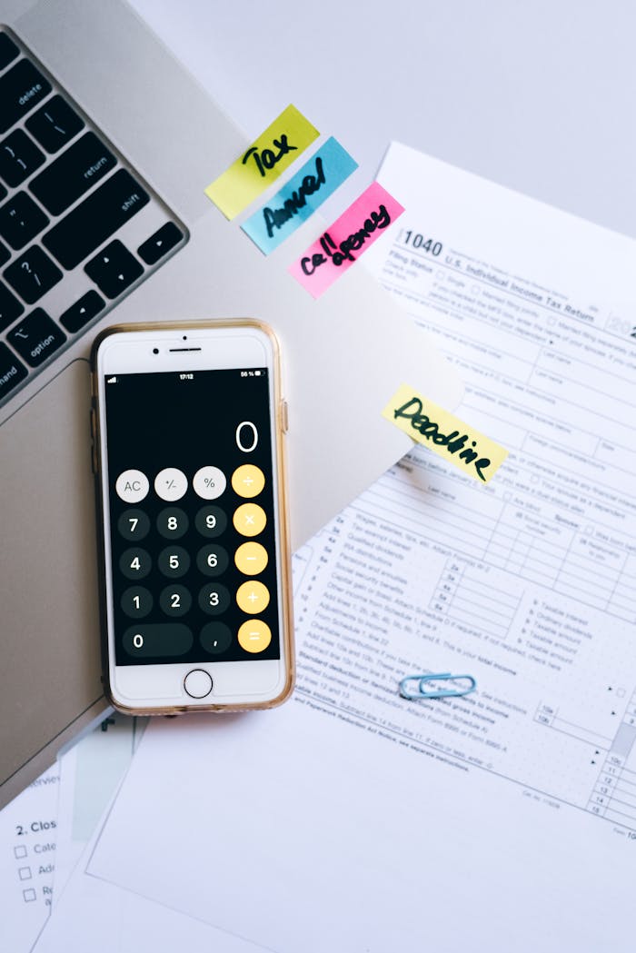 The Art of Drawing Readers In: Your attractive post title goes here A smartphone calculator and tax forms on a desk, symbolizing financial planning.